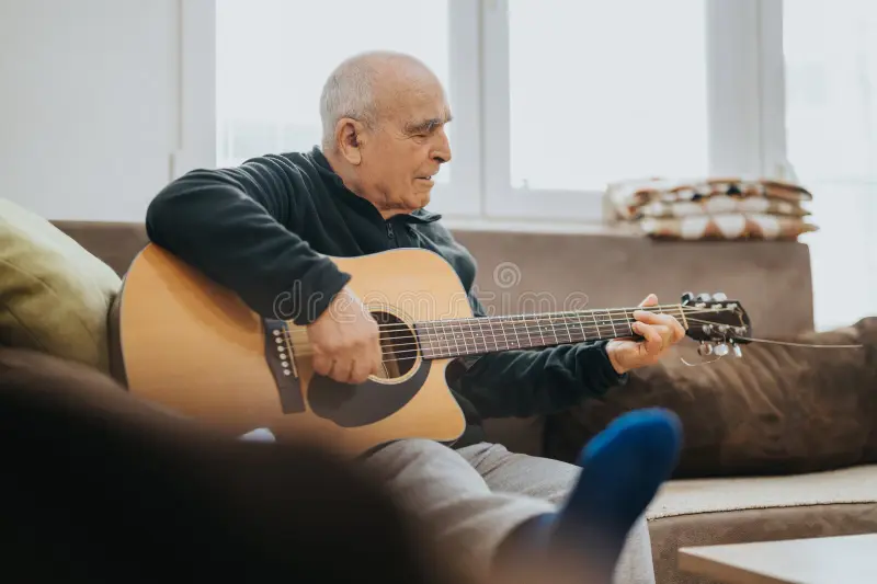 older man over 60 playing guitar part of a blog encouraging men over 60 to learn guitar