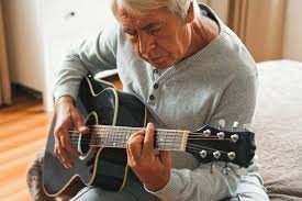 older man over 60 playing guitar part of a blog encouraging men over 60 to learn guitar