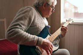 older man over 60 playing guitar part of a blog encouraging men over 60 to learn guitar