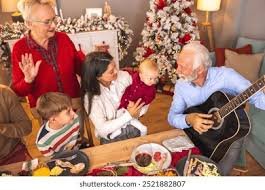 Older beginner playing Christmas guitar songs by the tree