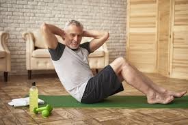 Older man over 60 performing sit-ups at home as part of a strength training routine