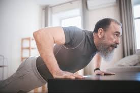 Older man over 60 performing desk pushups at home as part of a strength training routine